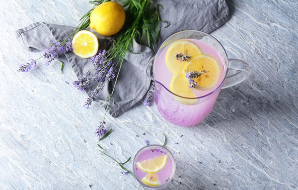 A pitcher of Lavender Fizz drink garnished with lavender buds.