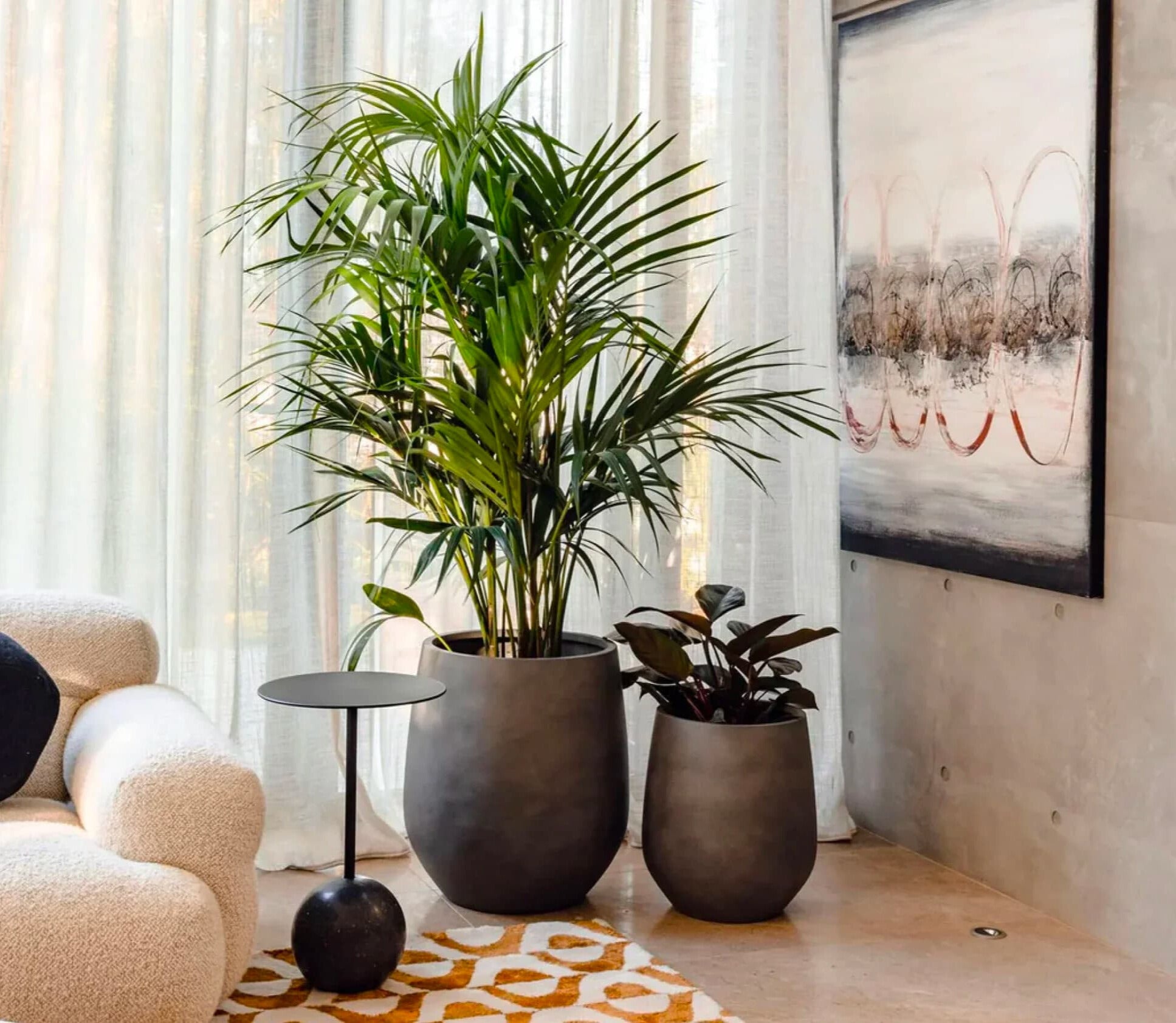 Elegant interior featuring tropical plants in chic matte planters by The Balcony Garden, enhancing the cozy ambiance near sheer curtains and contemporary art