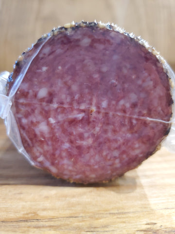 Cross section of a stick of soft, pepper coated salami. 