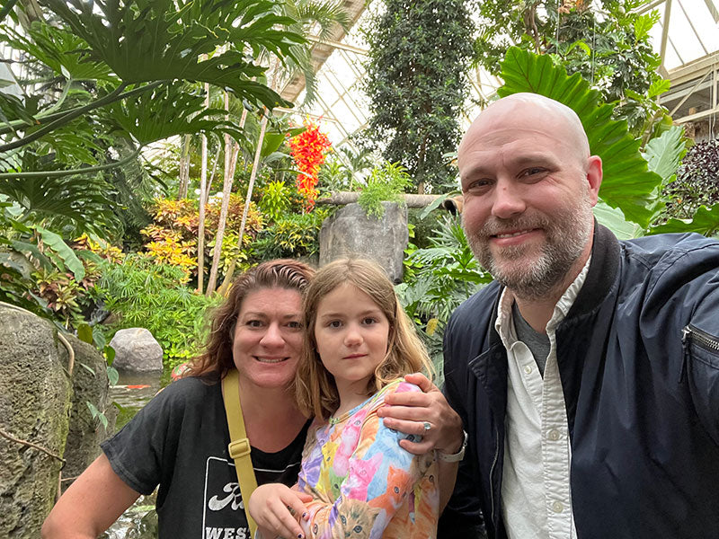 Doug, Violet and Laura Oldham at the Franklin Park Conservatory together in front of a koi pond