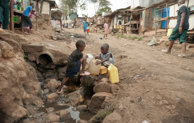 Alt: Two young boys collect water in a poor African village