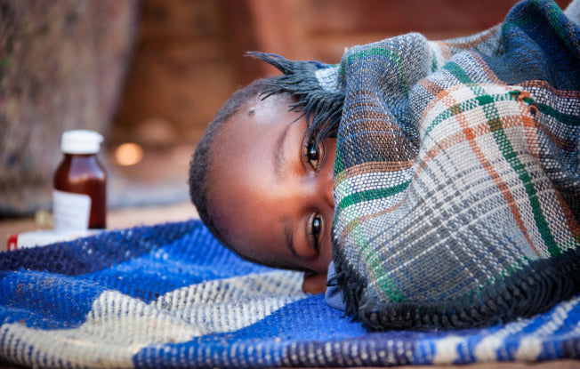 Alt: A young African child wrapped up in a warm blanket