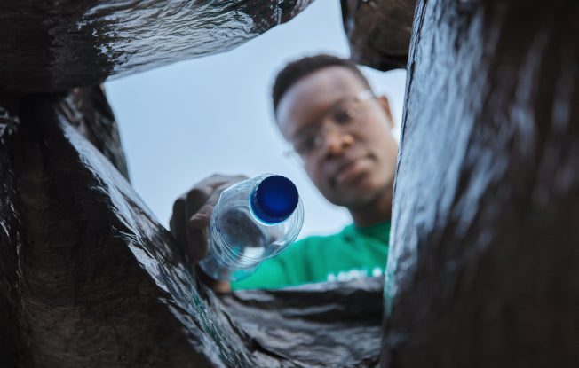 Alt: A man putting a plastic water bottle in a trash bag