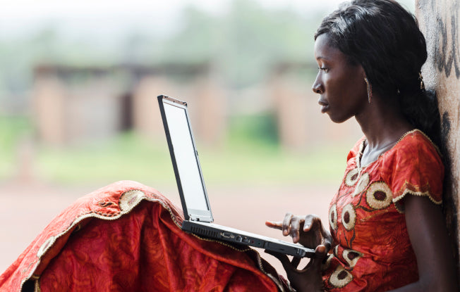 Alt: A young woman wearing traditional clothing on a laptop