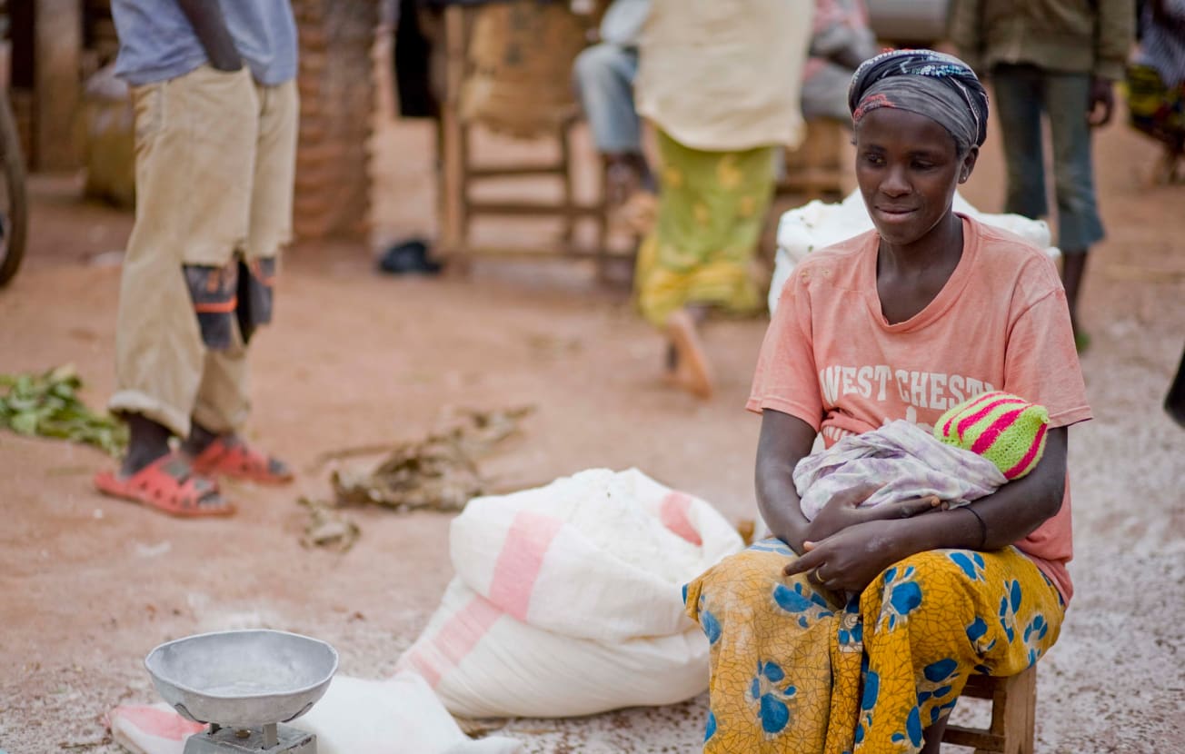 Alt: A young mother cradles her child in an African village