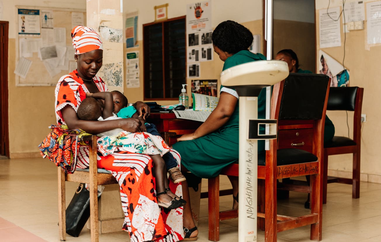 Alt: A mother holding her children in a hospital room in Africa.