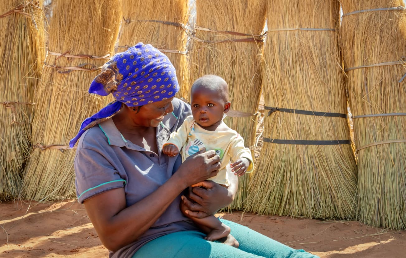 Alt: A smiling mother plays with her baby