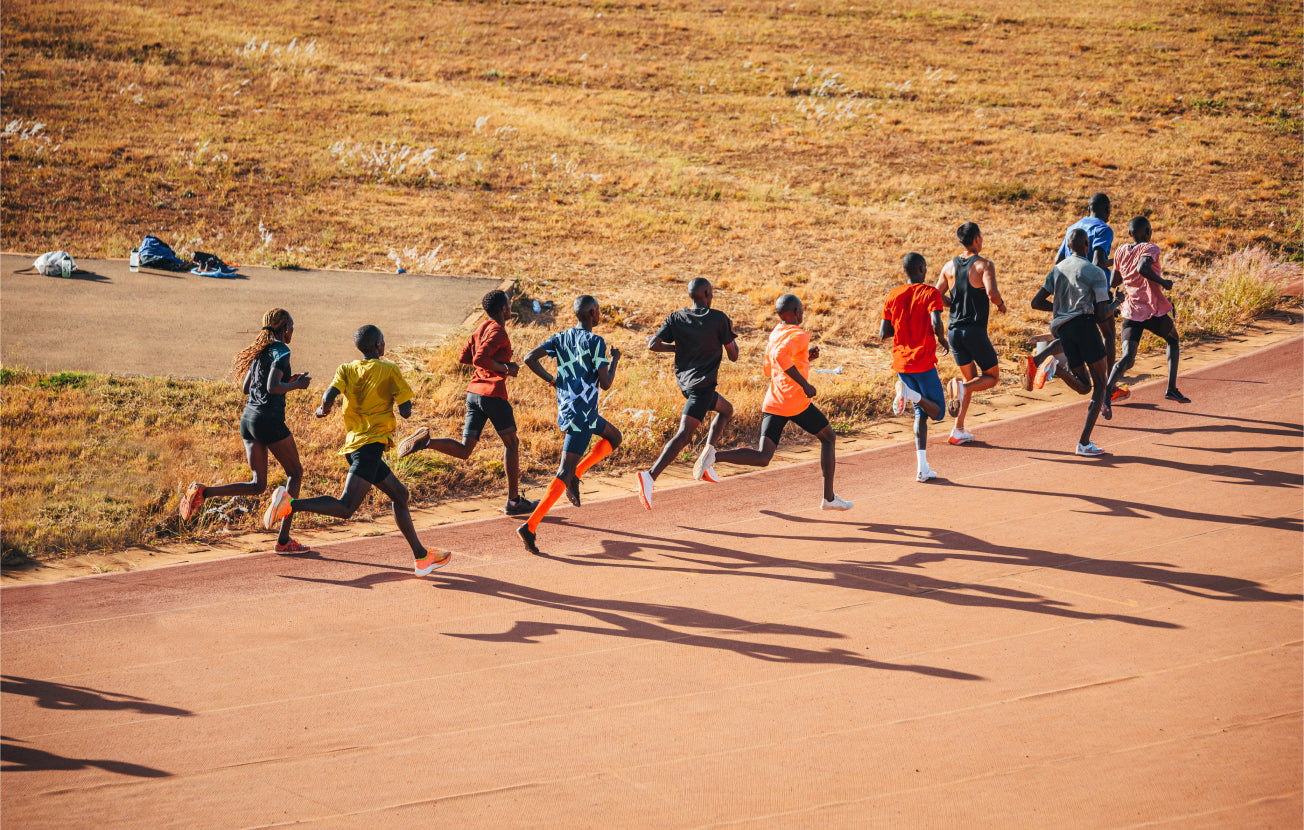 Alt: A group of marathon runners racing on a track in Africa.