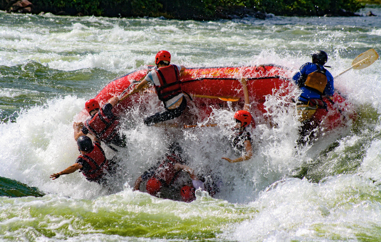 Alt: A group of people falling into choppy waters on a river rafting trip.