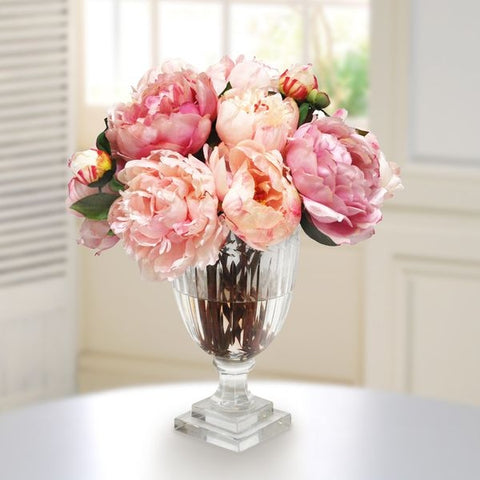 Variety of pink peonies arranged in glass vase