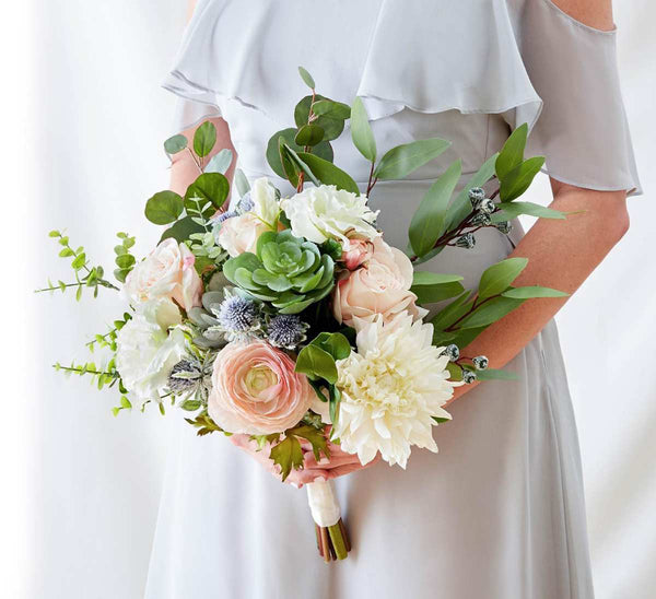 A woman holding a luxury white and pink rose faux floral bouquet