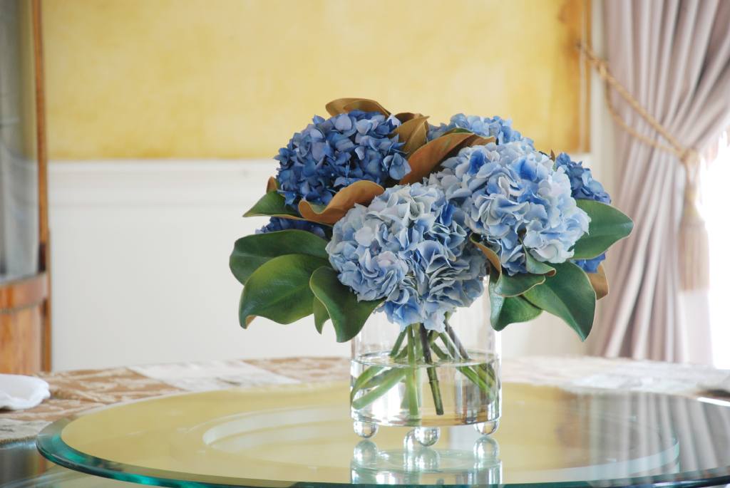 Faux blue hydrangea arrangement in glass vase