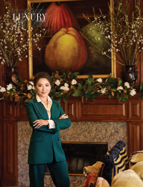 Victoria Tai in green suit standing in front of fireplace decorated with faux magnolia and cherry blossoms