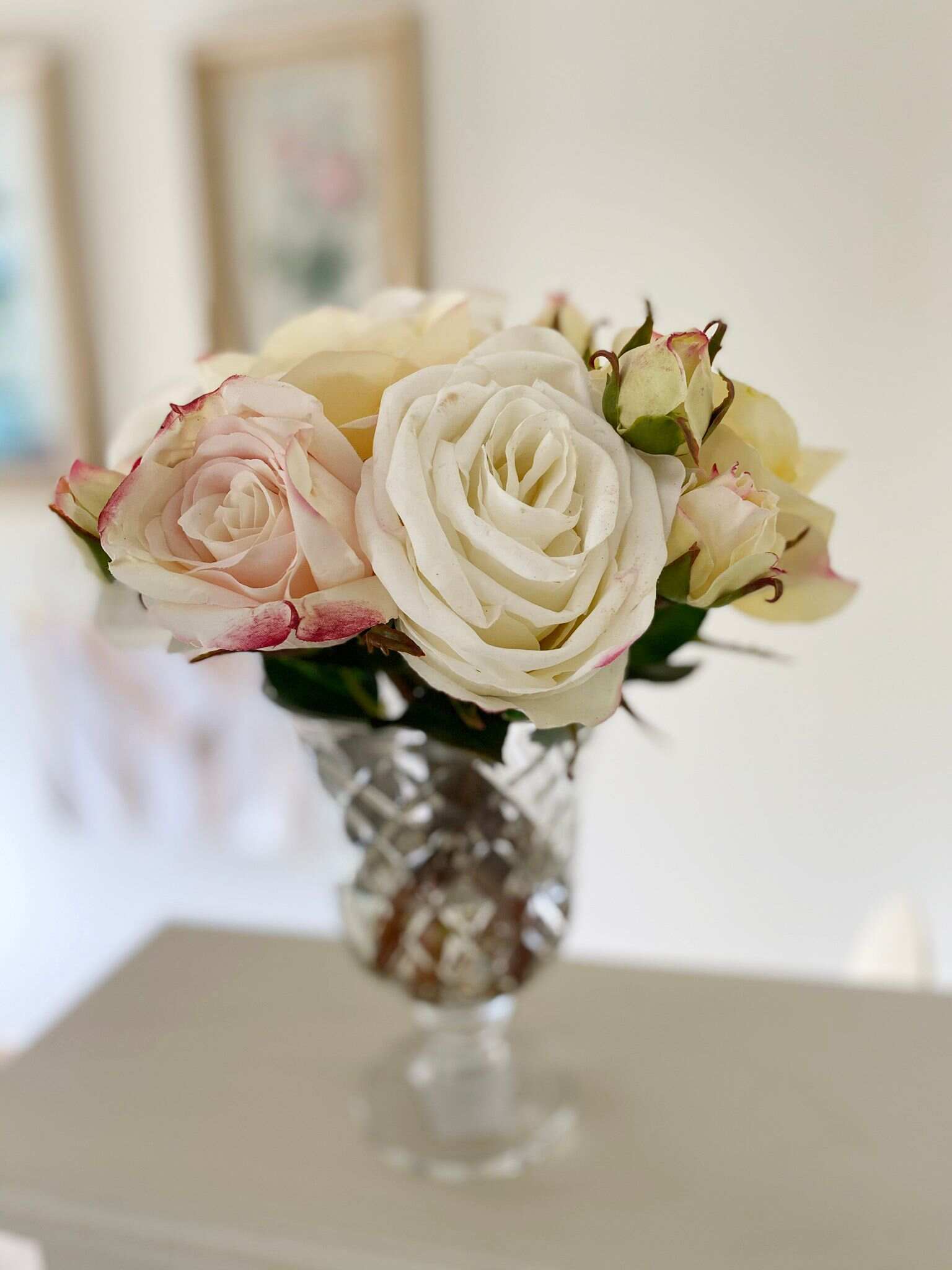 White artificial roses in cut glass vase on table