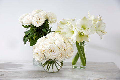 White roses and lilies in glass vases on a table 