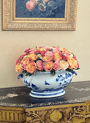 Large colorful faux rose arrangement in ornamental vase on entryway table