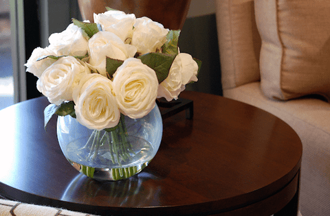 Compact white faux rose arrangement in glass vase on coffee table
