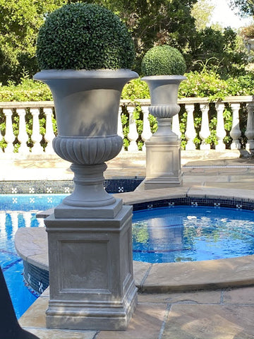 Boxwoods in urns used as patio decor near pool