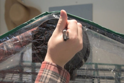 A man traces a black circle on the plastic of a tent.