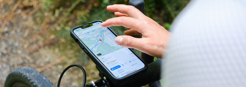 Cyclist checking they trail map on their phone. They are using a StrideCharge Charge Case and Bike Mount