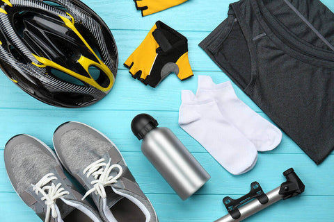 Cycling items on a blue background, which include a bike helmet, shoes, gloves, water bottle, tire pump, socks, and a shirt