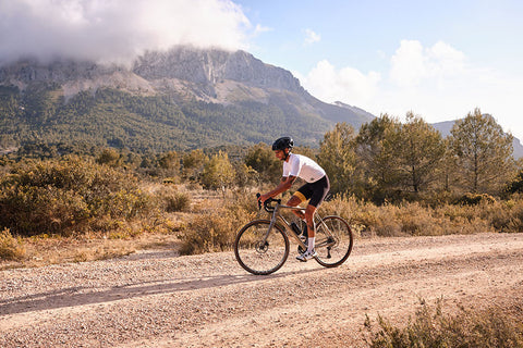 A cyclist wearing essential gravel riding gear, such as a helmet, gloves, and shoes