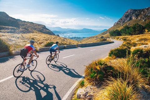 A person cycling on a road with a beautiful landscape in the background