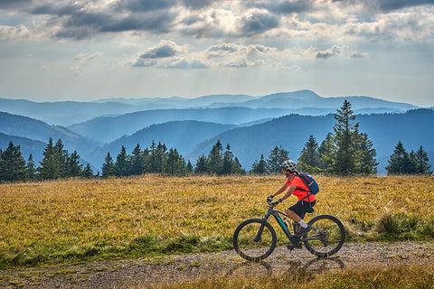 A person cycling outdoors, showing the benefits of exercise for reducing heart disease risk factors