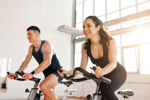 An image of two people riding an indoor cycling bike in a well-lit room, showcasing the ideal setup for indoor cycling.