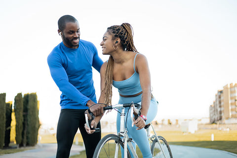 A person learning to ride a bike with the help of a friend