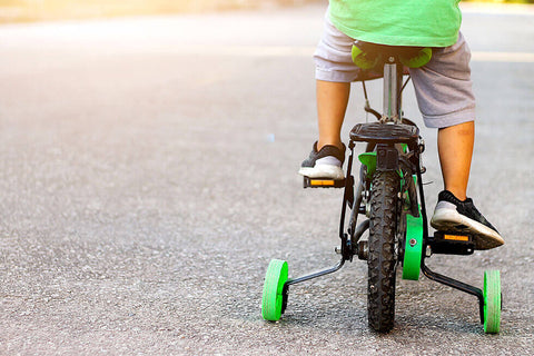 A person riding a bike in a straight line with training wheels