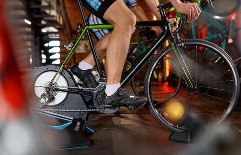 A person riding a stationary bike in a gym, strengthening their lower body muscles