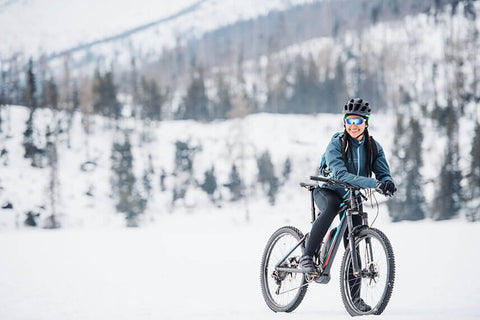 A cyclist outdoors in the snow in winter training gear, planning a training plan for the winter season