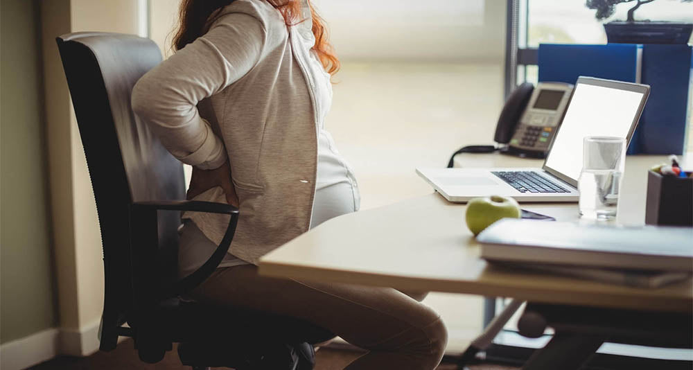 Pregnant businesswoman looking uncomfortable at work desk