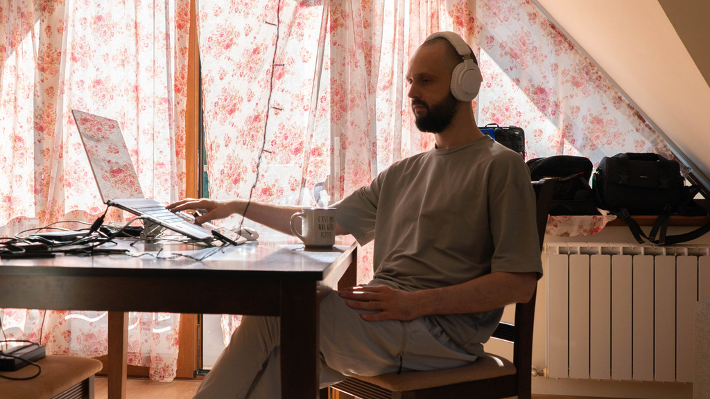 Oleg Oleg Zvyagintsev, a beflo digital creator and collaborator sitting and listening to music in a moody quiet space with floral curtains