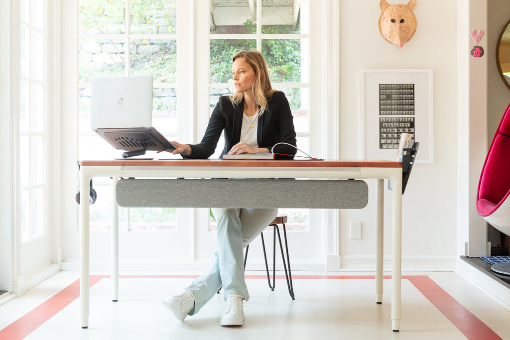 WFH Professional working at beflo Tenon sit-stand luxury desk in a bright white room with lots of natural light