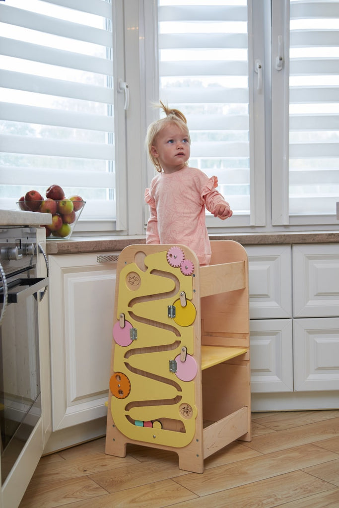 A child helps in the kitchen with the help of a learning tower