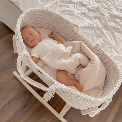 Cream crochet moses basket with a sleeping baby