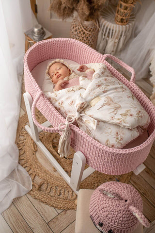 Baby in a pink moses basket