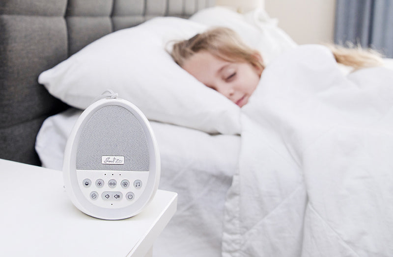 Sweet Zzz white noise machine on a nightstand next to a child