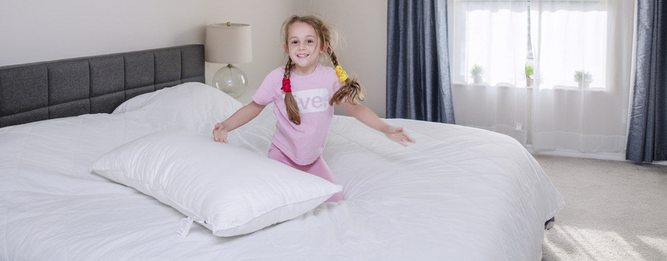 a girl playing on the bed with sleeper pillow