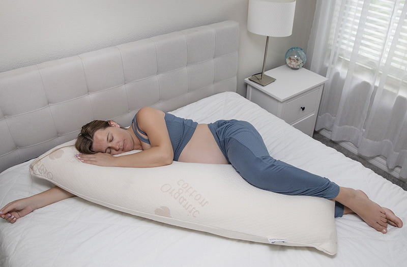 pregnent lady hugging a Sweet Zzz body pillow on a mattress