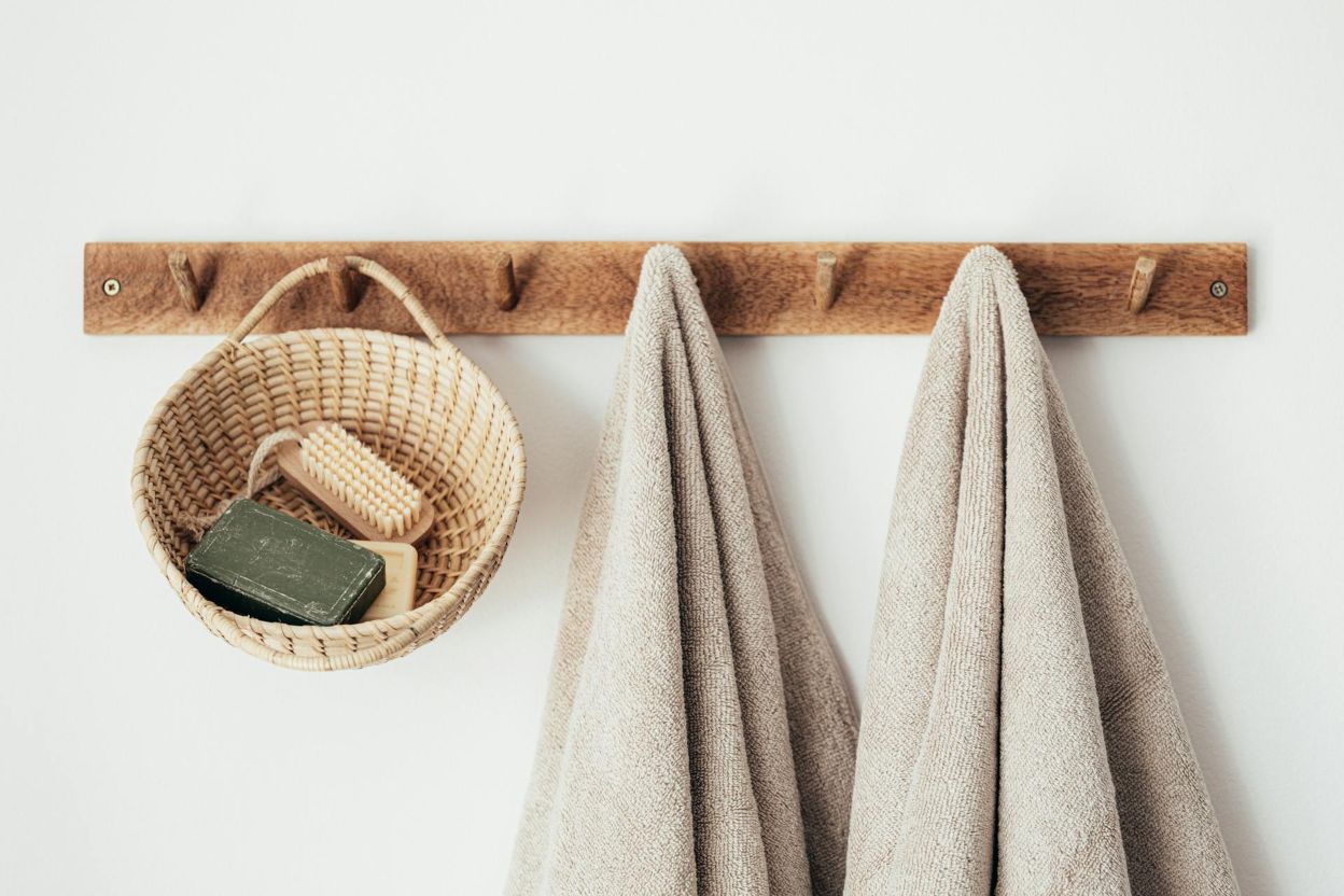 A wooden wall hanger with towels and baskets hanging off it