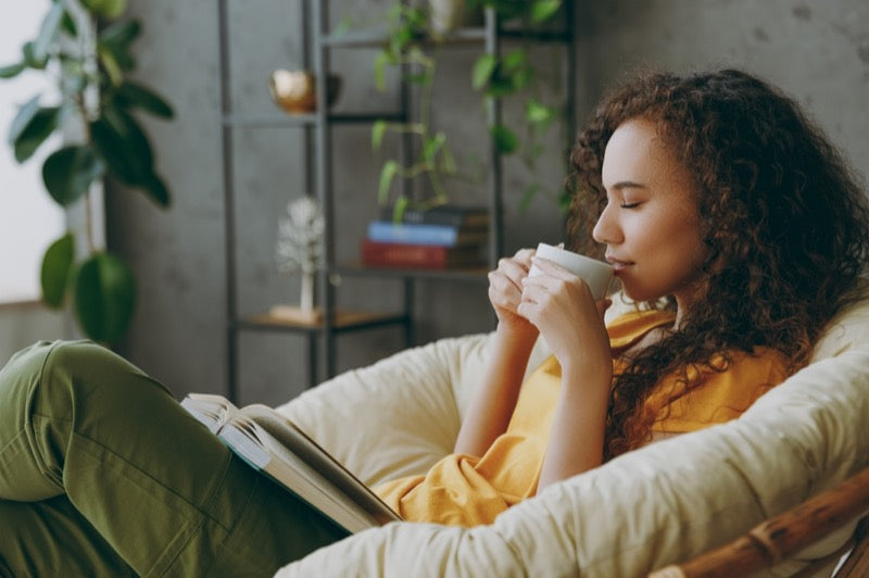 Sideways young woman of African American ethnicity wear t-shirt drink coffee