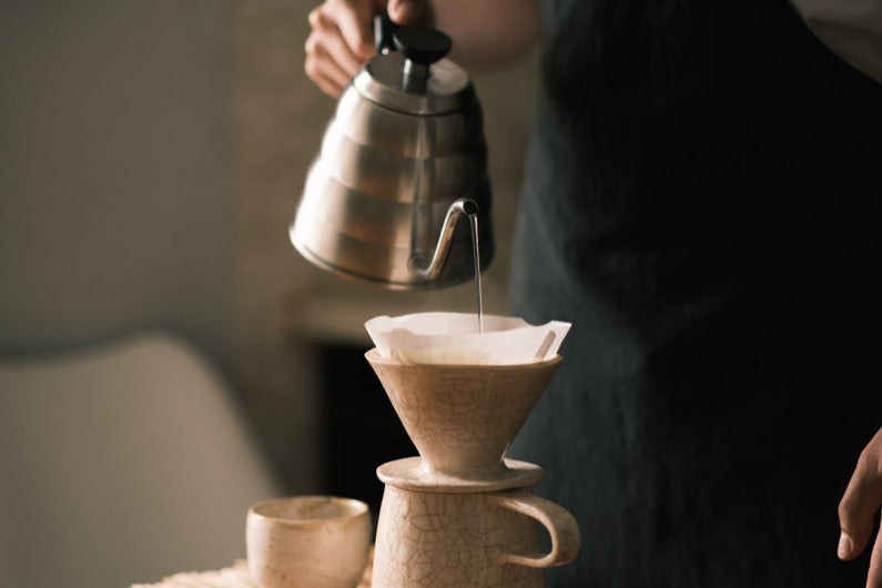 Brewing pourover coffee in the kitchen, pouring hot water on the