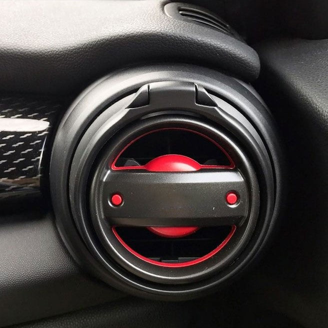 A black car cup holder with two drink slots and additional space for small items, mounted in a Mini Cooper's cup holder slot.