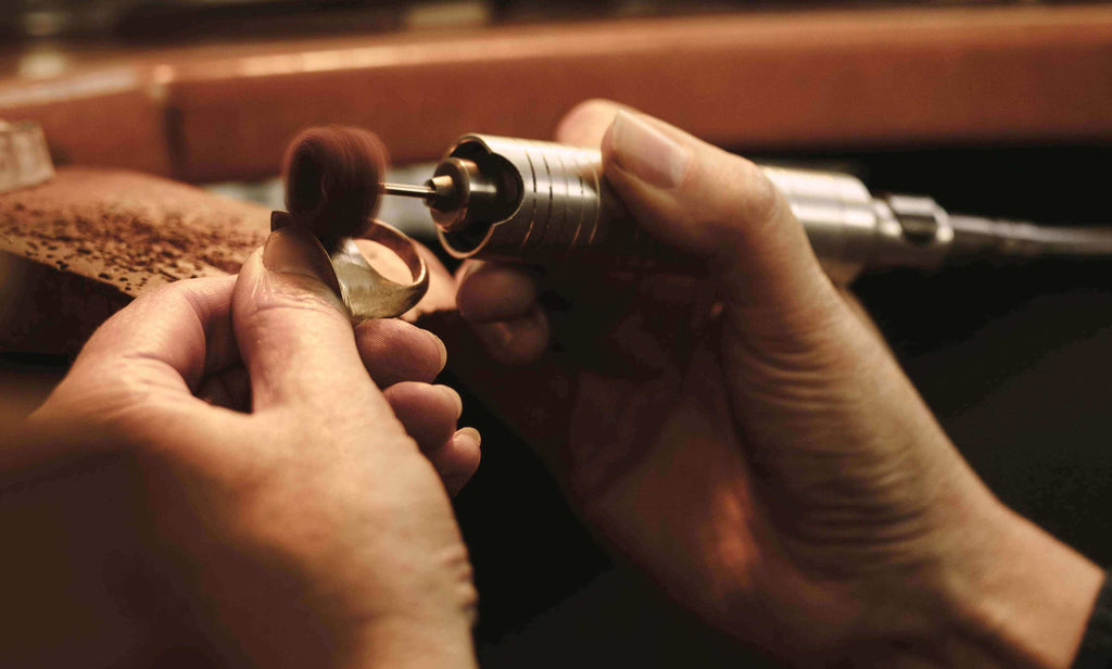 Jeweler using a buffeting tool to smoothen out a custom made ring