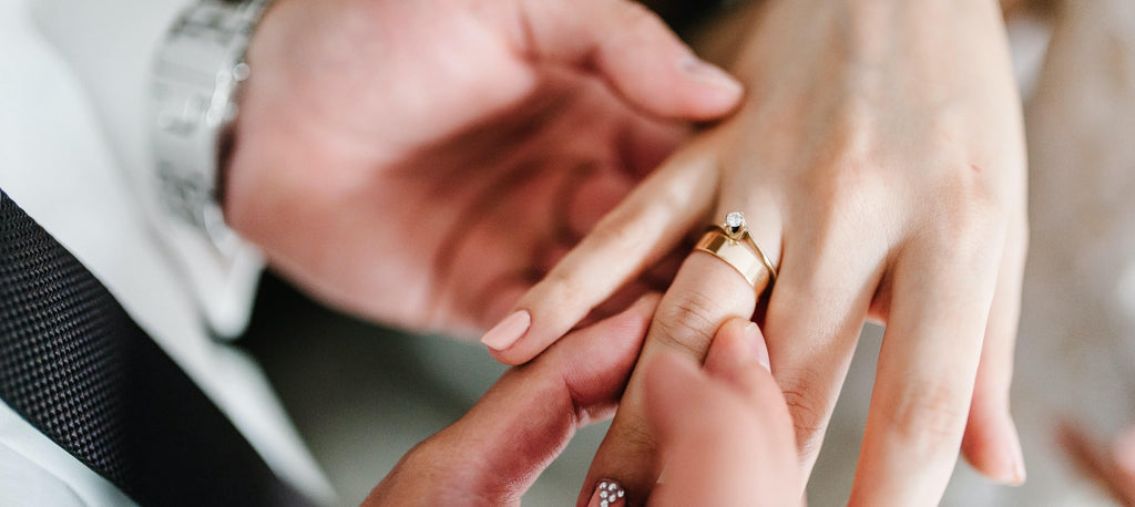 Man stacking rings on a woman's ring finger.