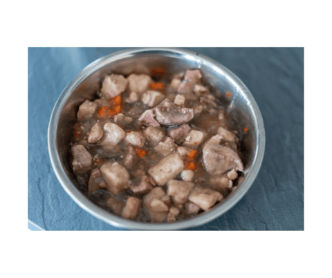 A bowl of meat and vegetable wet food for dogs on a blue-grey background