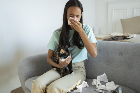 An infected woman sneezes into a tissue while holding on to her pet. Zoonotic diseases can infect both people and pets.